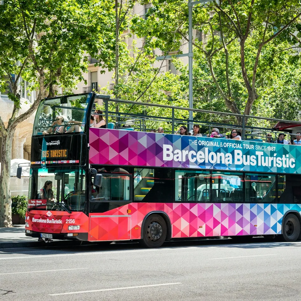 Barcelona Bus Turístic sightseeing bus beneath roadside trees