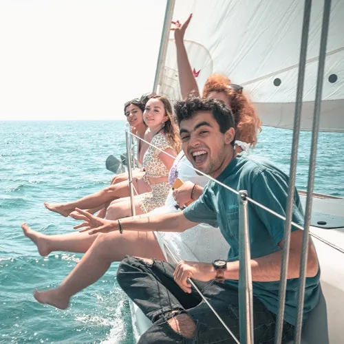 Guests relaxing with their legs over the side of a sailing yacht
