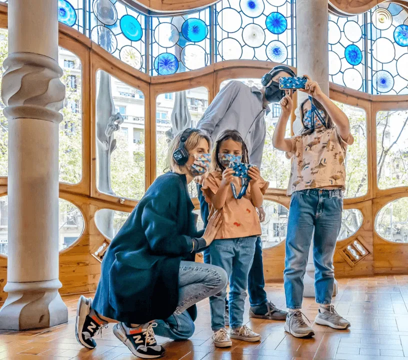 Visitors using handheld devices beside curved windows inside Casa Batlló