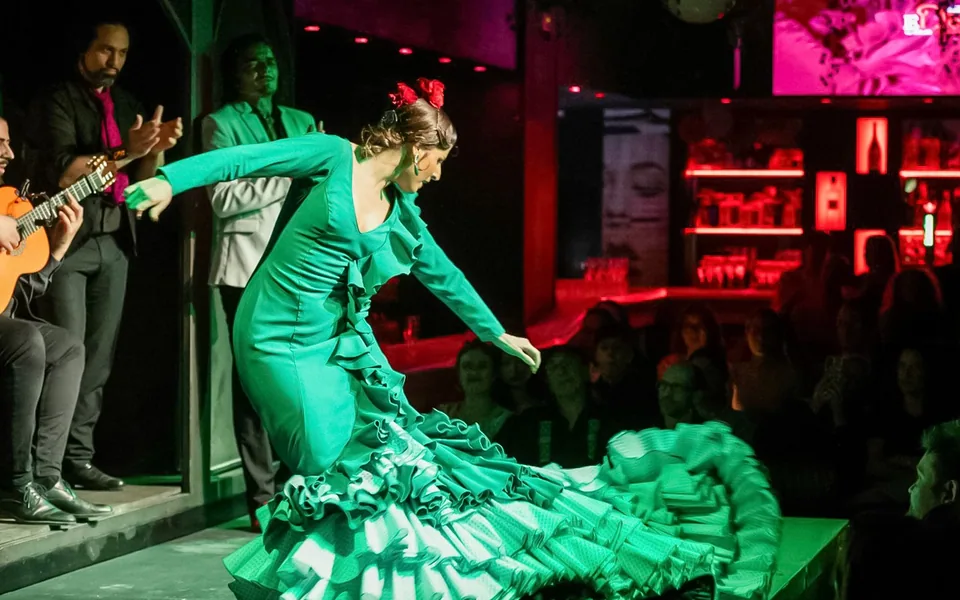 Flamenco dancer sweeping a green dress across the El Duende stage