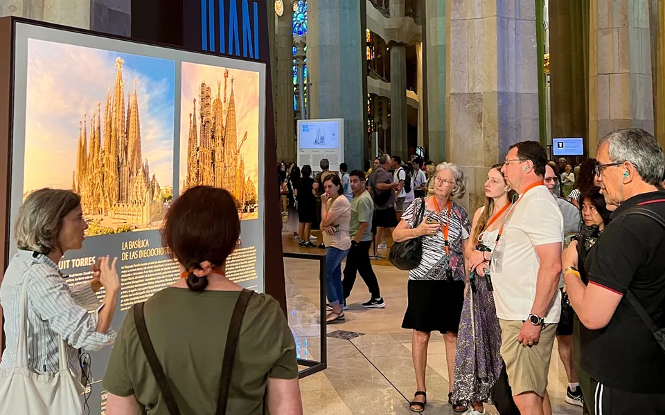Visitors listening to a guide beside a Sagrada Família interpretation panel