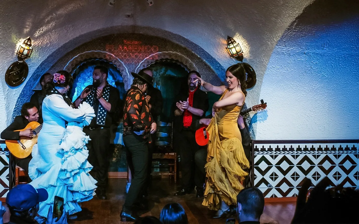 Flamenco dancers and guitarist beneath arches at Tablao Cordobés